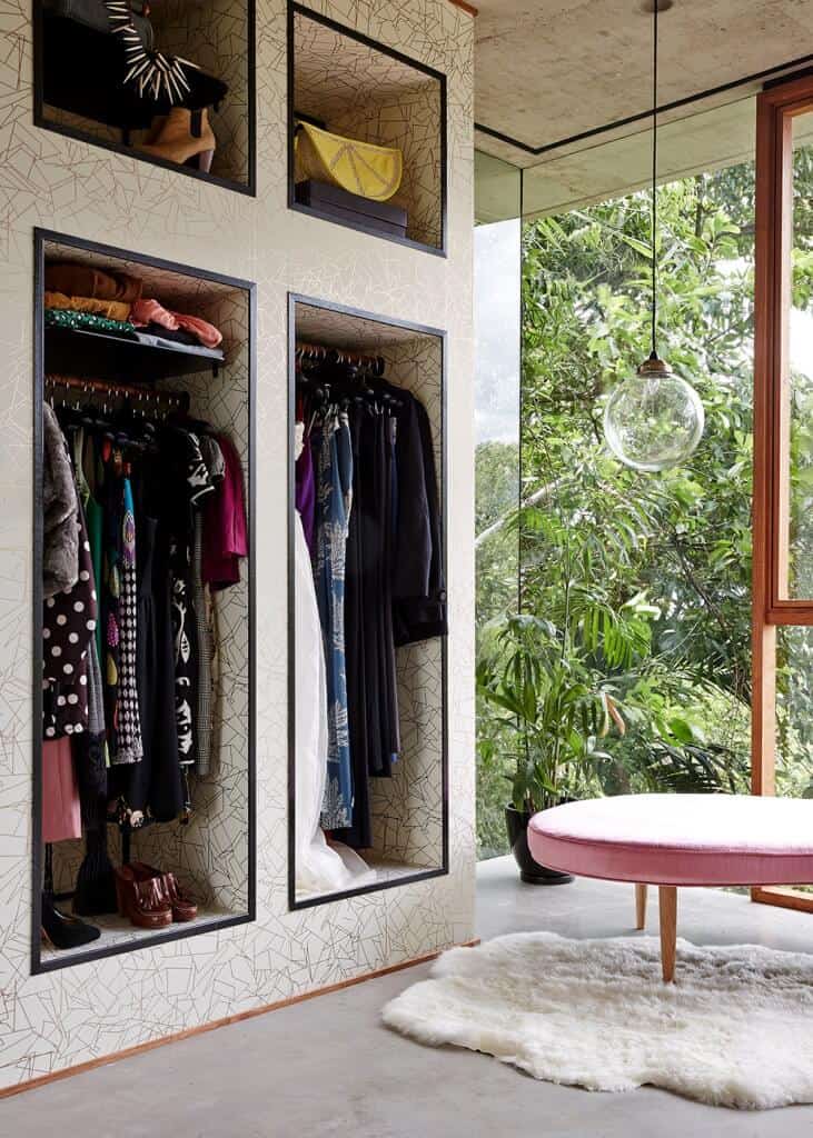 卧室壁橱设有时尚的橱柜，设置在地毯地板上。玻璃墙和窗户俯瞰着美丽的室外区域。