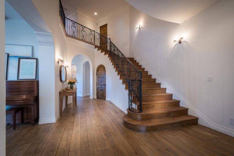 沿着门厅的木制楼梯配有木质拱形门，设有华丽的栏杆。它由固定在白墙上的壁灯照明。