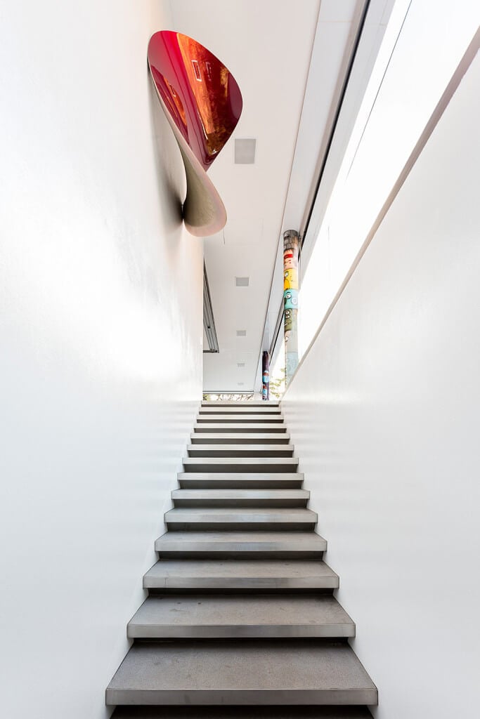 混凝土直楼梯固定在白色墙壁上，并由彩色凹艺术品强调。