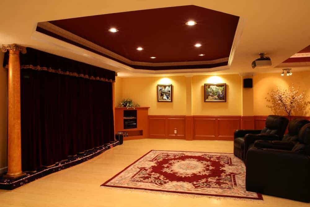一个大型家庭影院，拥有优雅的墙壁和天花板，以及硬木地板，上面有美丽的地毯。