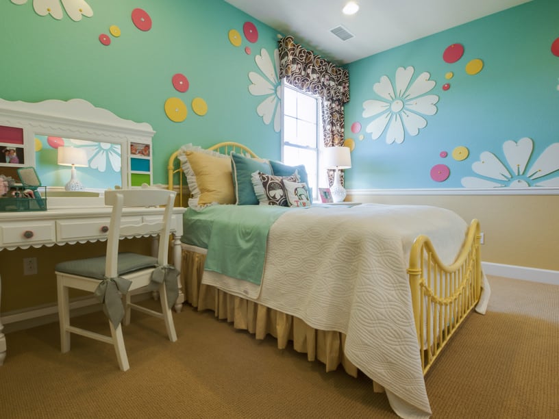 一个可爱的女孩的卧室，可爱的墙壁装饰在绿色的墙壁上。地毯地板增加了卧室的格调。