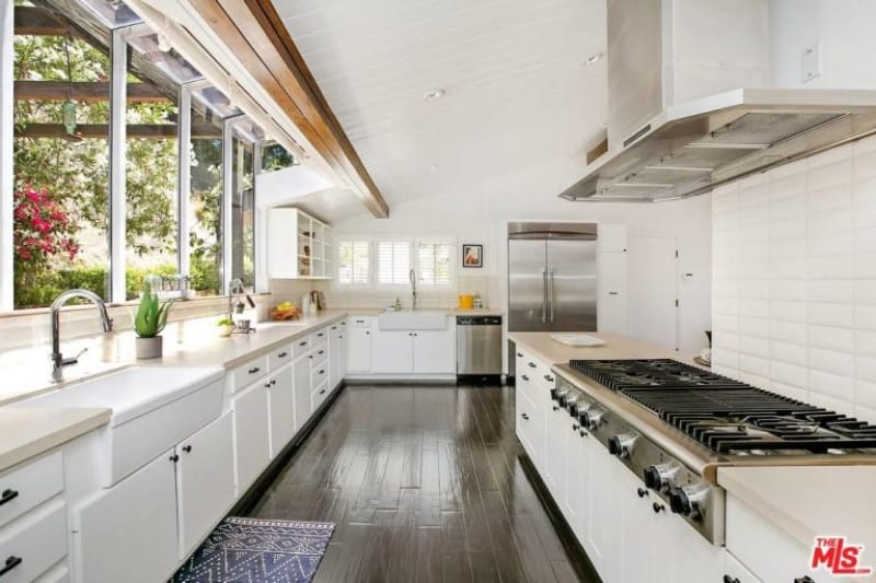 白色厨房设有黑色硬木地板和白色厨房柜台，简单而优雅的台面。