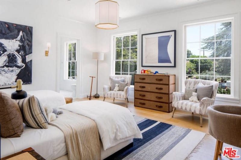 白色的现代客房与对比鲜明的颜色从墙上的绘画，多色地毯和可爱的家具。