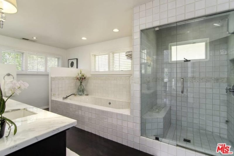 这个美丽的设计，浴缸的瓷砖沿着淋浴间向上延伸，使它看起来几何，时髦，现代，同时仍然保持经典的黑白单色主题