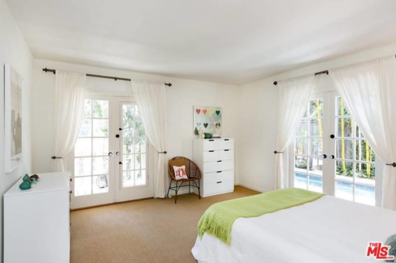 这间平静的、铺着白色地毯的卧室是一个完美的放松场所，享受从双玻璃门进入的自然采光。