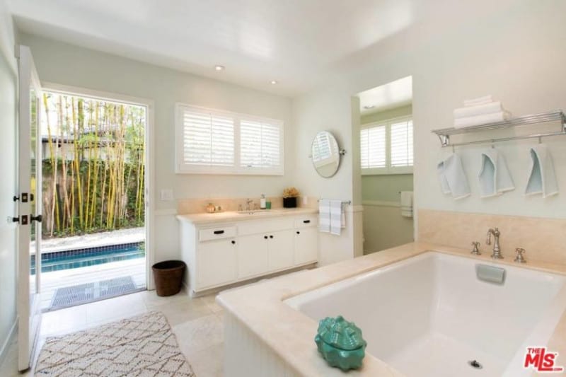 文斯·沃恩(Vince Vaughn)家的现代浴室设计的例子，从台面和浴缸看到的桃红色装饰，淋浴区的入口和铺着地毯的主入口，方便进入游泳池。
