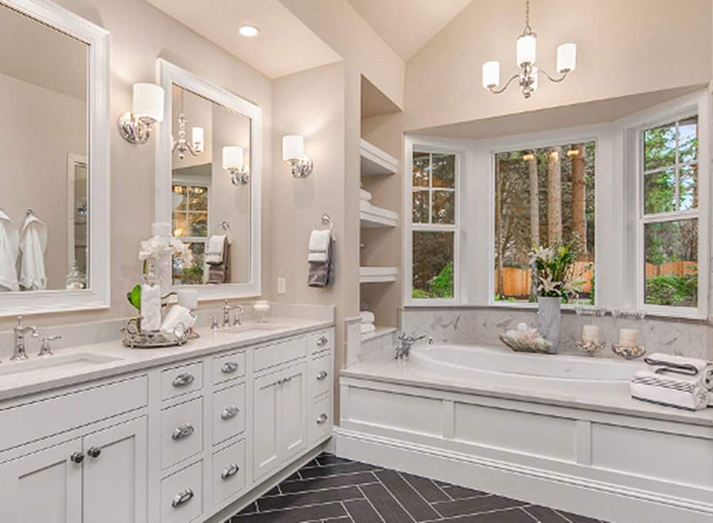 地板上的黑色人字形瓷砖与梳妆台的白色橱柜形成了鲜明的对比，与浴缸的底座很好地搭配在一起。