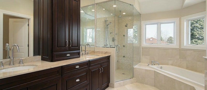 宽敞的米黄色主浴室，带玻璃淋浴，窗边的浴缸和双洗手池。