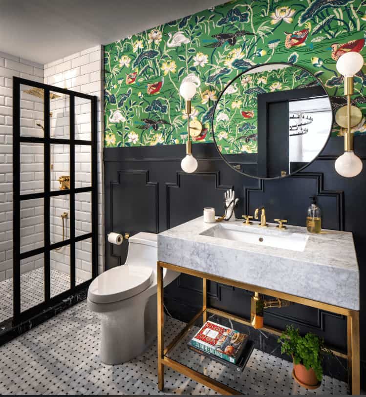 折衷的浴室提供了一面圆形镜子，两侧是黄铜壁灯，与固定装置和顶部有白色大理石柜台的洗手台相辅相成。