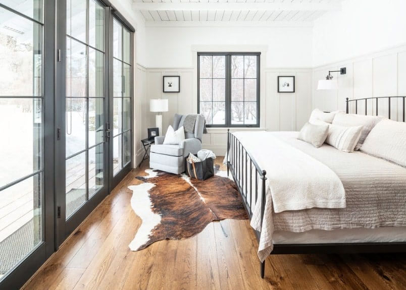 角落卧室设有特大号金属框架床，人造牛皮地毯铺在硬木地板上。这个空间还包括一张软垫躺椅、几面木板和木条墙、一面木条天花板，以及通往一处平台的滑动玻璃门。