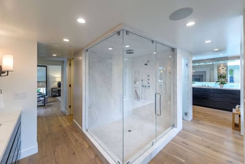 这现代浴室酷的硬木地板和一个令人印象深刻的大理石淋浴室是一个很好的混合新旧。水槽软,重点照明,而相反的区域大理石台面有灯笼灯。