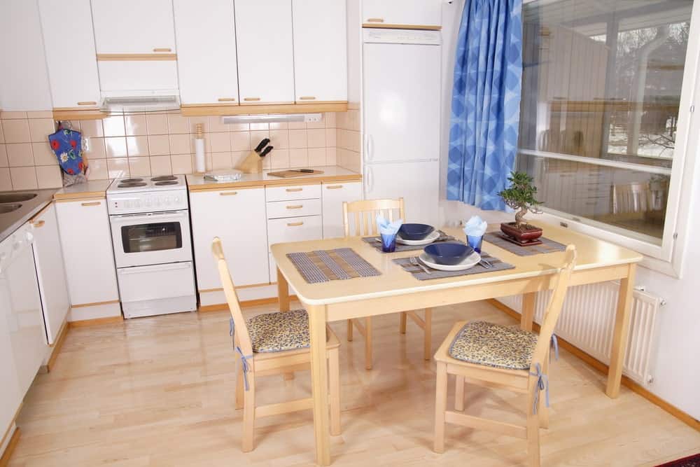 用餐式厨房设有白色橱柜和轻木餐桌，配套的椅子与浅色硬木地板相辅相成。