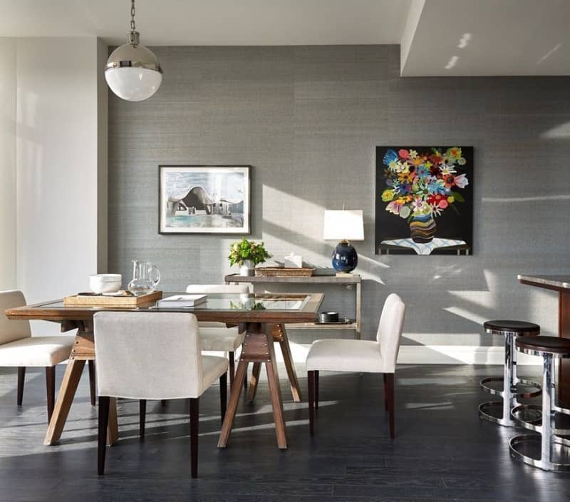 灰色的餐厅空间设计有墙壁帆布和框架，以及一个球形吊灯。它包括一张玻璃台面的餐桌，用木质和白色椅子围成框架，铺在深色硬木地板上。