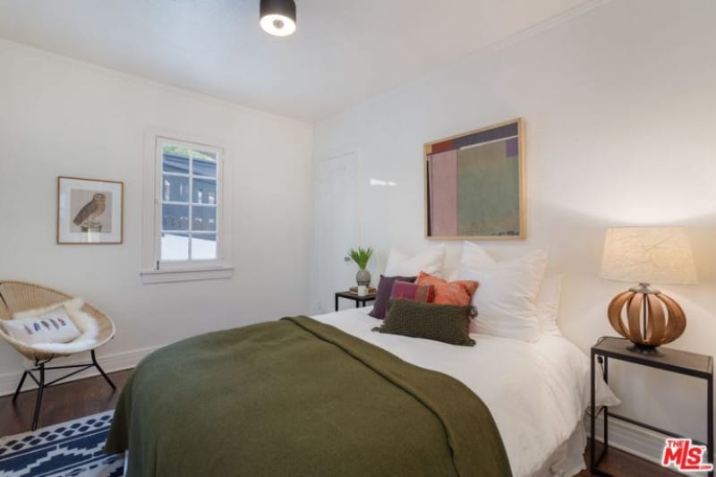 这间极简主义风格的小客房漆成白色，设计简单，有侧灯、装裱的艺术品和一个小开窗。