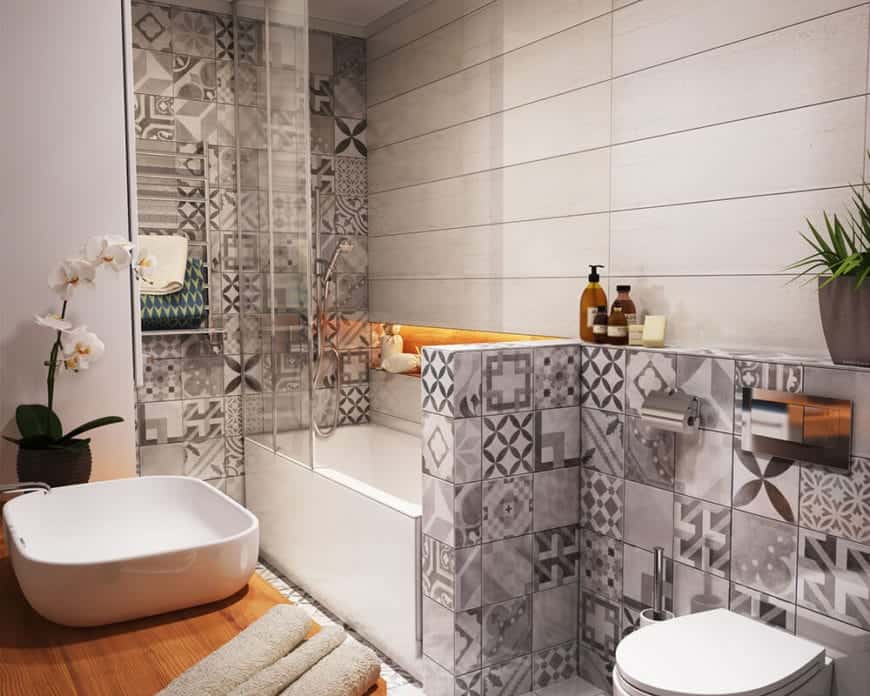 这个斯堪的纳维亚风格的浴室墙壁和地板上有灰色图案的瓷砖，与之相辅相成的是木质梳妆台上的白色水槽，以及白色的马桶和浴缸，它还兼作淋浴区，以节省空间。