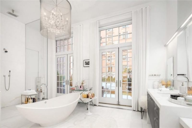 位于曼哈顿的顶层公寓曾是音乐人兼演员詹妮弗·洛佩兹(Jennifer Lopez)的房子，主浴室的特色是一个悬挂在高高的天花板上的当代烛光吊灯。房间采用白色配色和意大利大理石板地板设计，在开放式淋浴间前设置了一个独立的拖鞋浴缸，浴缸两端凸起倾斜。