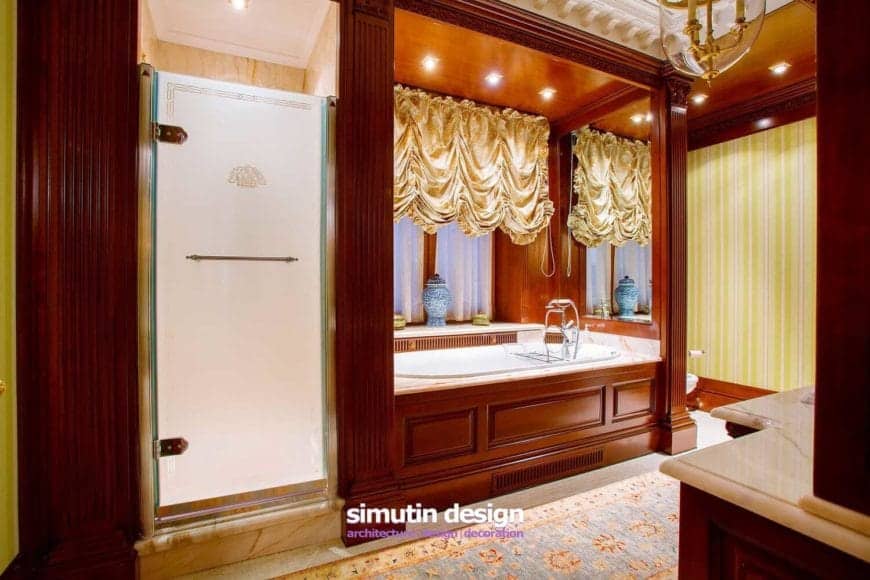 这个戏剧性而浪漫的主浴室有一个木制凹室，里面有浴缸，上面有镜子和针灯，照亮了与黄色条纹壁纸相匹配的黄色窗帘。