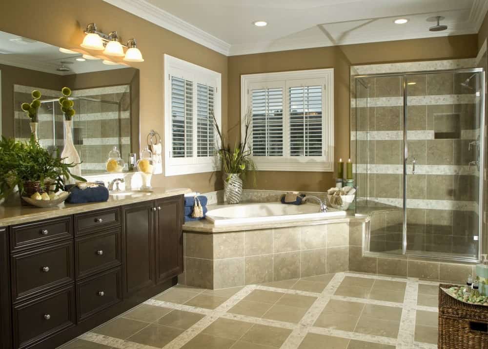 淋浴区的瓷砖墙壁和地板有一种图案，这种图案在浴室其他部分的地板上得到了反映，浴缸旁边的梳妆台放在角落里，有两扇百叶窗。