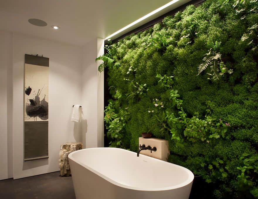主浴室设有一个独立的浴缸，前面是垂直植被的绿色墙壁。