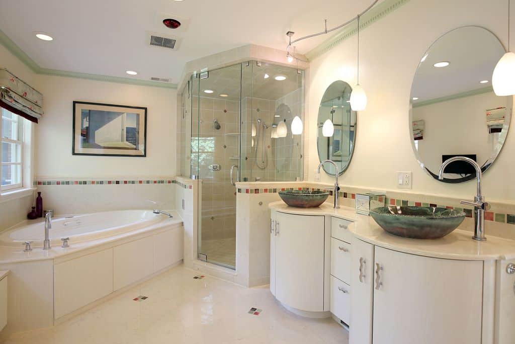 主浴室设有两个绿色陶瓷容器水槽和抛光铬水龙头。这个空间还包括悬挂在大理石台面梳妆台上方的吊灯、两面大圆形镜子、一个浴缸和带玻璃门的步入式淋浴房。浴缸和淋浴间有额外的嵌入式照明和一扇窗户。