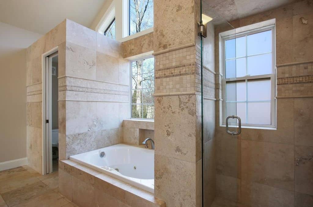精心制作的大理石瓷砖使这间主浴室与众不同，设有一个浸入式浴缸和玻璃封闭式步入式淋浴间。该空间还包括硬木地板和带天窗的拱形天花板，以吸收自然光。