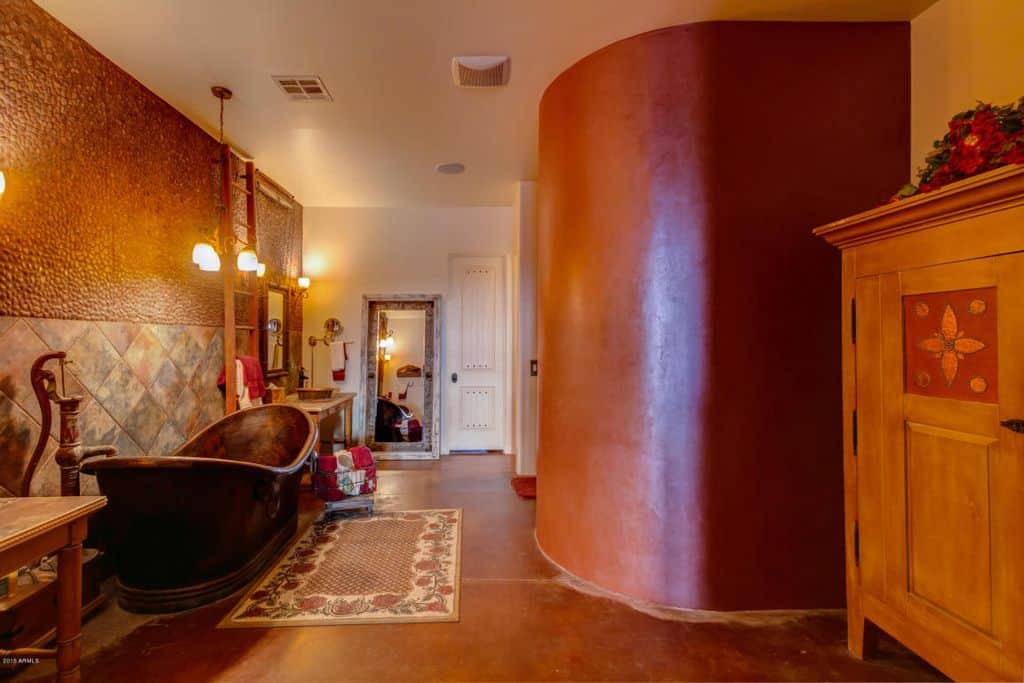 温暖的浴室，独立浴缸和木制洗手台，旁边是步入式淋浴。它包括一个储物柜和用作毛巾架的木梯。