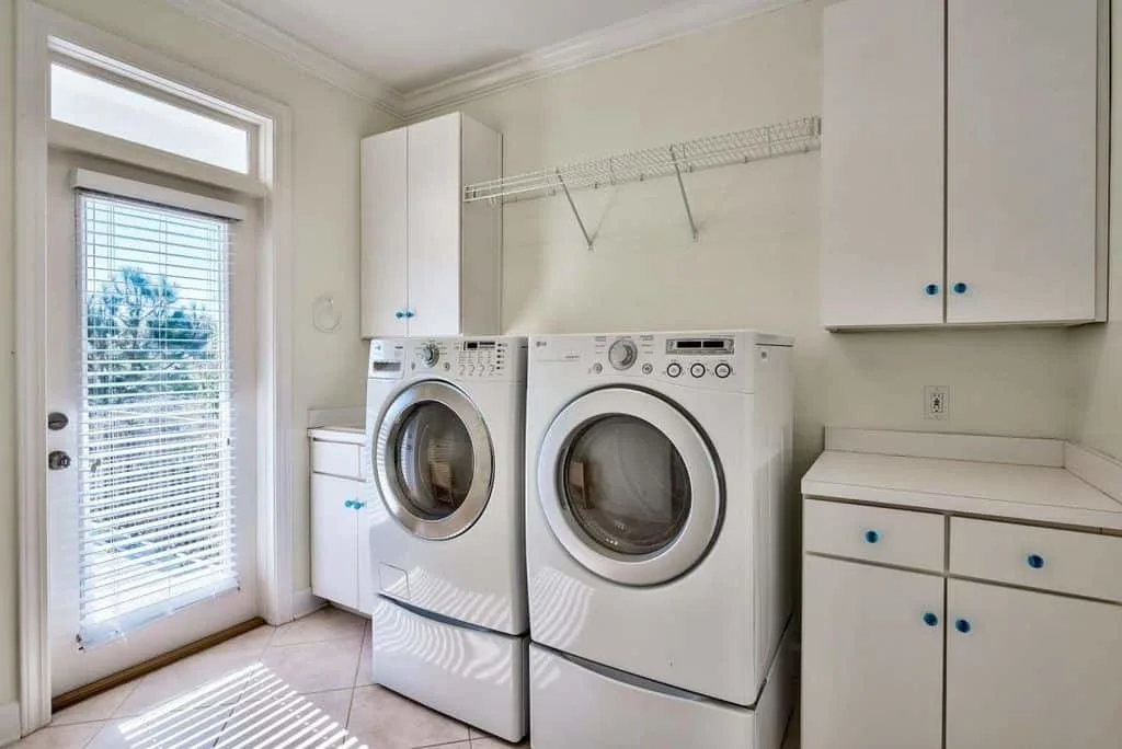 洗衣房高架洗衣机/干衣机的组合特性,储存柜和大型玻璃门进入后院。