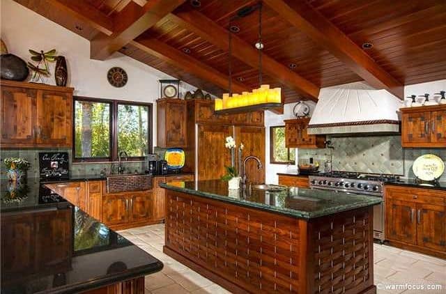 一个令人惊叹的厨房，带木棚天花板，露出横梁和瓷砖地板。厨房的柜台和黑色花岗岩台面一起看起来很有吸引力。