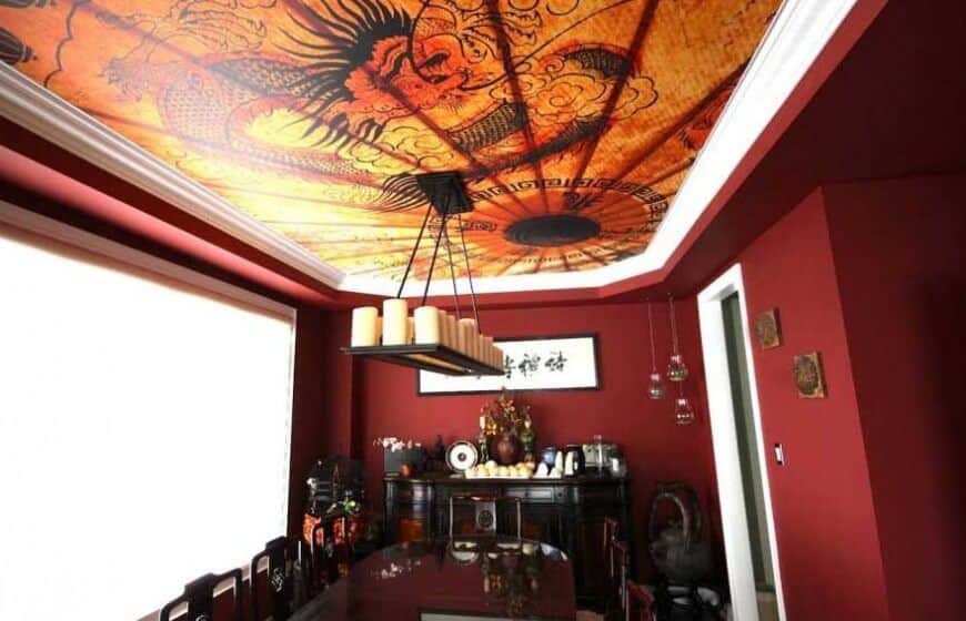 这个美丽的红色房间采用了中国设计，定制的照片天花板上有一条龙。灯具在桌子上方有一系列柱状蜡烛。