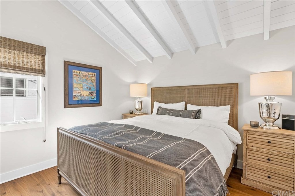 木床和配套的床头柜与白色的墙壁和天花板相得益彰。它的风格是圆滑的鼓台灯和一个框艺术品，为房间带来了流行的色彩。