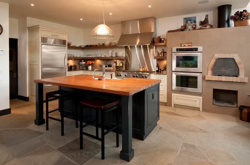 乡村风格的厨房，带砖砌壁炉，内置搁架代替壁柜，铺石板瓷砖地板。