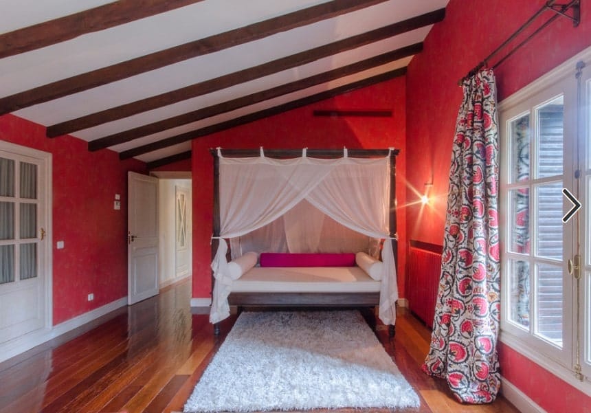 主卧室采用硬木地板，红墙和带横梁的棚顶。房间有一个可爱的床设置以及。