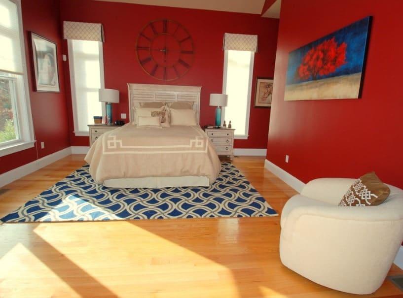 主卧室有一个优雅的床设置，由两盏台灯照明，周围是红墙。
