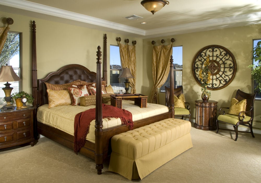 圆形华丽的墙壁艺术为这间主卧室增添了一个不错的特色，舒适的座椅和一张四柱床，两侧是木制床头柜和传统台灯。