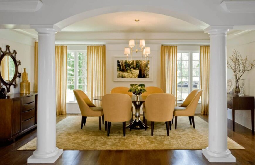 优雅的餐厅区，白色的柱子和覆盖着黄色透明窗帘的落地窗，与区域地毯和圆形靠背餐椅相得益彰。