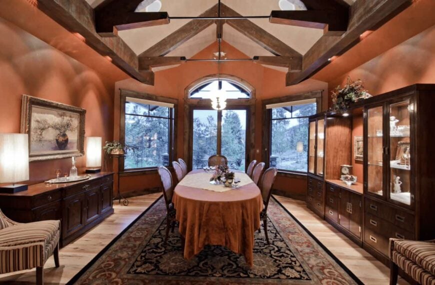 正式的餐厅，轻木地板和拱形天花板框架与木梁。它包括一个经典的餐厅设置在复古区域地毯放置在展示柜和自助餐桌之间。