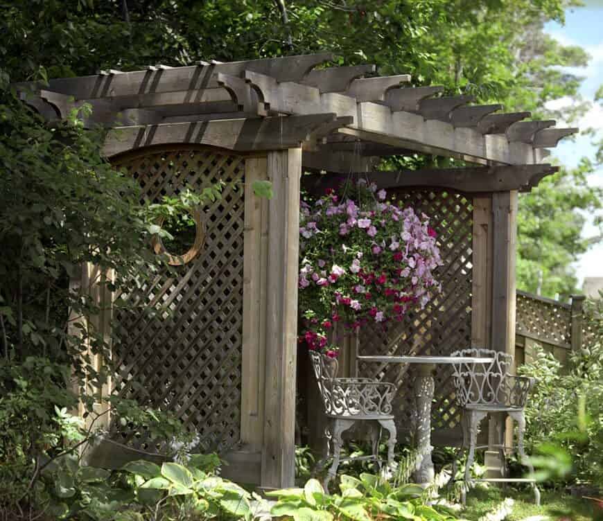 这个凉棚的柱子之间有格子，保持空间的浪漫。它被鲜艳的花朵覆盖，是一个很棒的花园坐地。