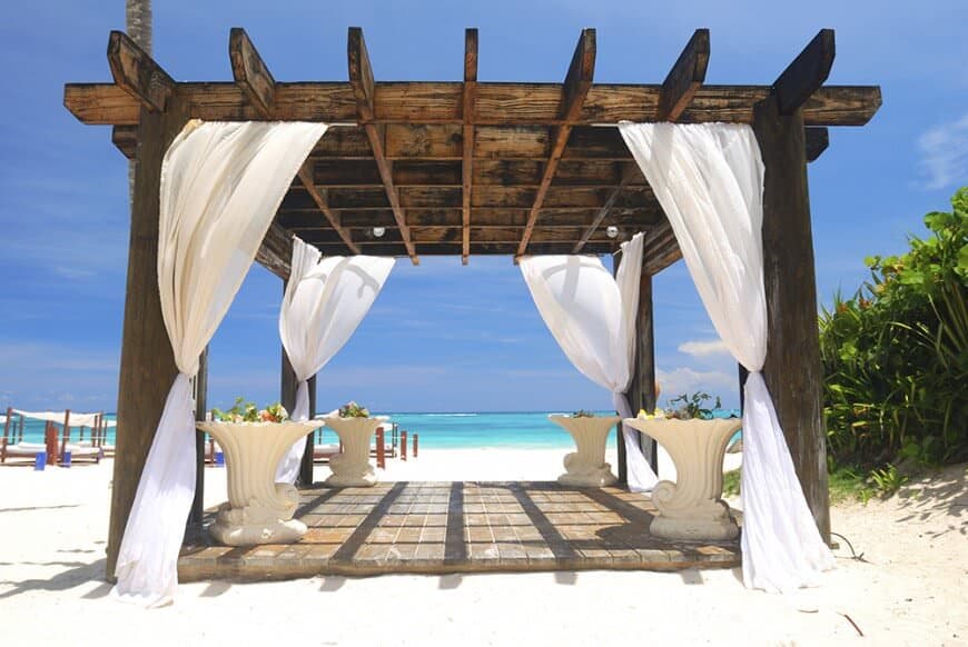 藤架也是完美的私人庭院。这个深色的藤架上有微风般的白色窗帘，可以在海滩上拉上一些隐私。