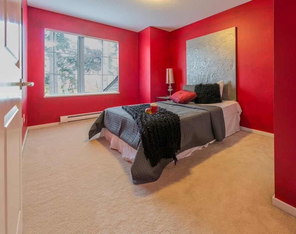 主卧室设有舒适的床和有吸引力的墙壁装饰。房间的特色是红墙和地毯地板。