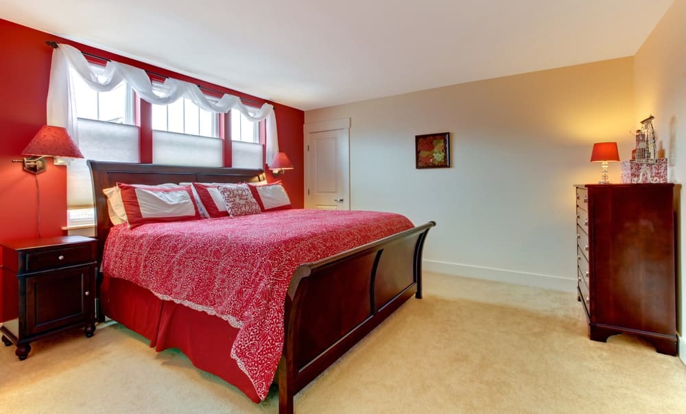 主卧室拥有一个大的优雅的床设置，周围环绕着红色和白色的墙壁以及地毯地板。