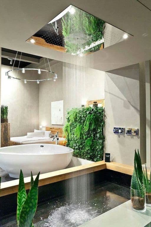 这间迷人的热带风格浴室就在卧室旁边，没有任何墙壁。它的头顶上有一个淋浴间，看起来像下雨一样，淋浴区装饰着芦荟植物。旁边是白色的独立浴缸，旁边有一圈植物。