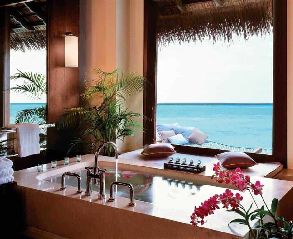 浴缸的浅粉色大理石外壳被从高高的窗户射进来的大量自然光照亮，窗户上有美妙的海景，让你有一种在阳光和海浪中沐浴的感觉。