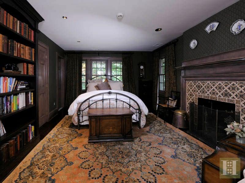 传统的主卧室有黑色的室内壁纸，内置书架，壁炉和漂亮的地毯地板。