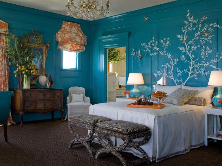 折衷的蓝色主卧室，墙上有壁画，橙色的窗帘和地毯地板。