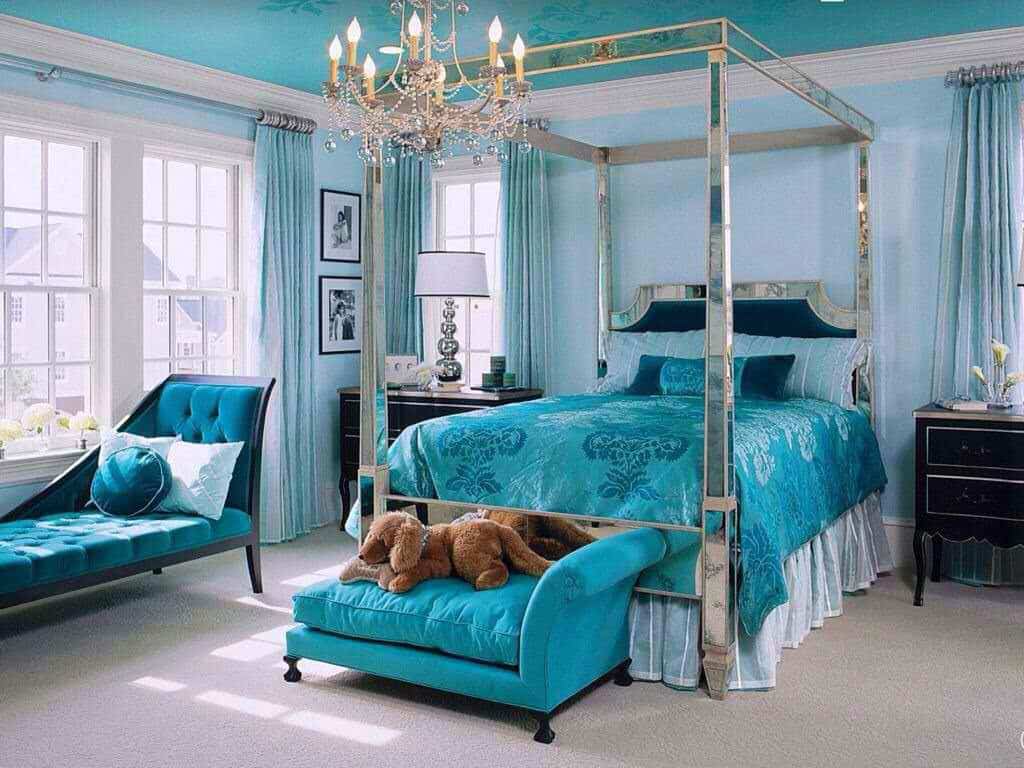 这间不拘一格的主卧室使吊灯和四柱床框在蓝色背景下闪闪发光。