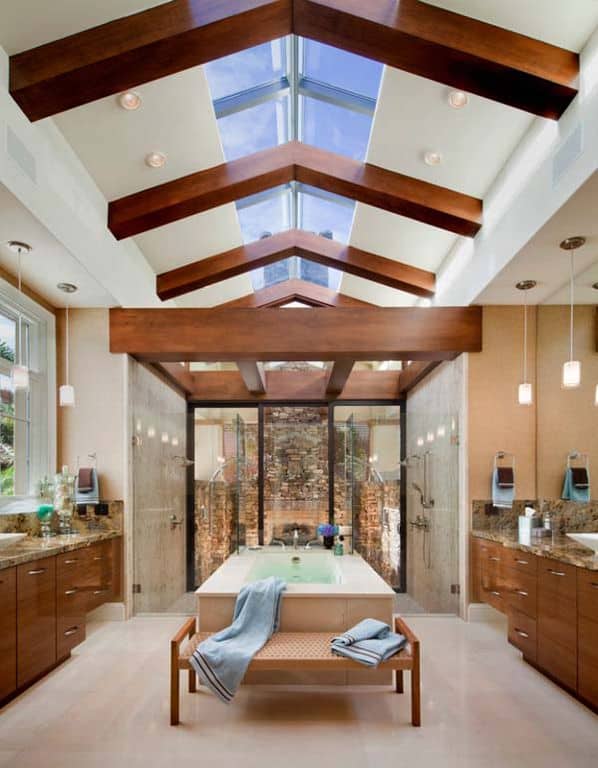 当代风格的主浴室带有裸露的横梁天花板、天窗和开放式淋浴旁的落地式浴缸。