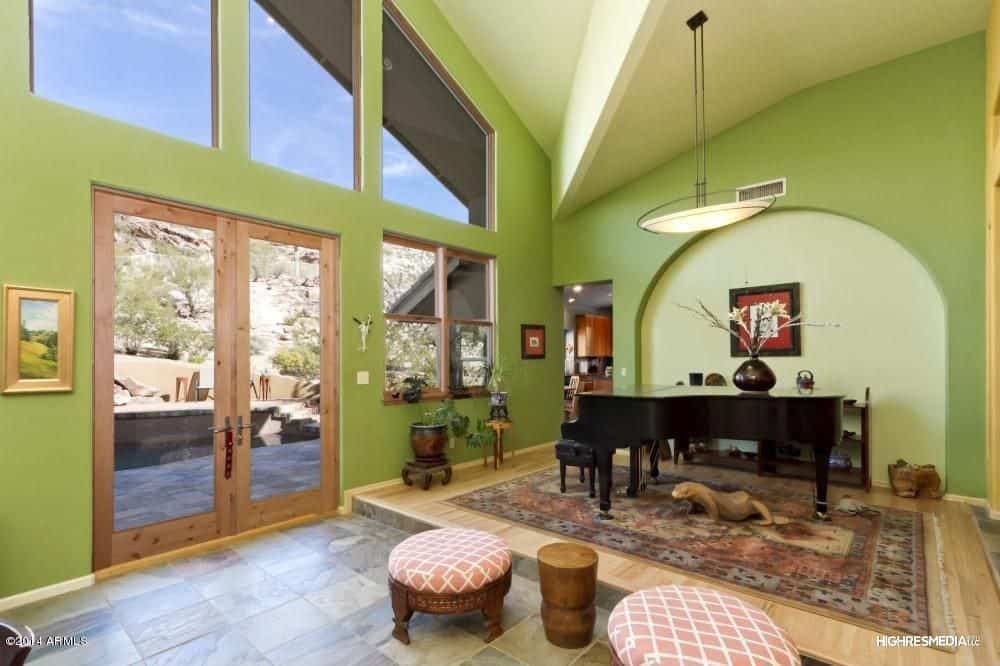 宽敞的门厅以浅绿色的墙壁和玻璃门窗为特色，允许充足的自然光线进入。它有一架大钢琴，由悬挂在拱形天花板上的吊灯照亮。