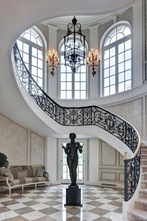 这个优雅的门厅拥有一个雕像设置在瓷砖地板上。旁边的沙发与华丽的墙壁和楼梯完美契合。