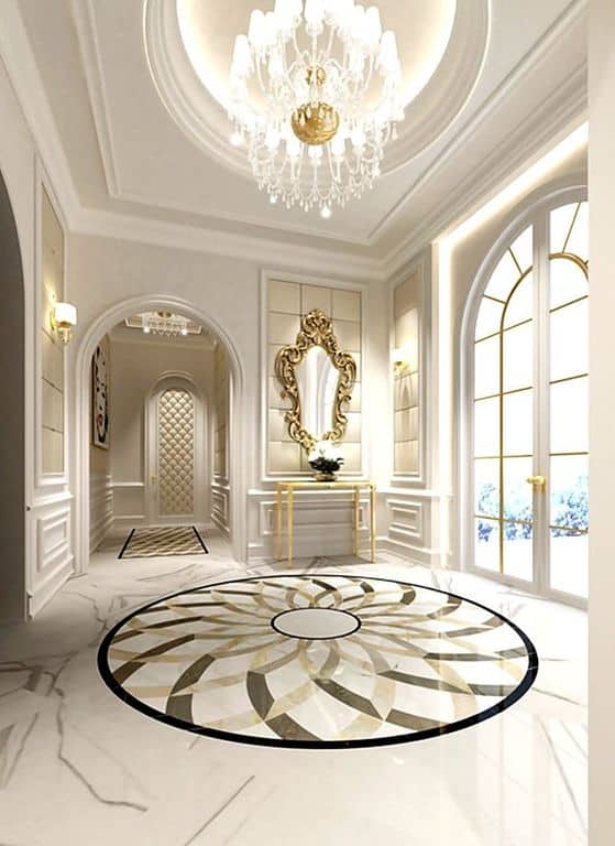 这个优雅的门厅拥有时尚的地板，白色的墙壁加上优雅的镀金细节和一个大吊灯。