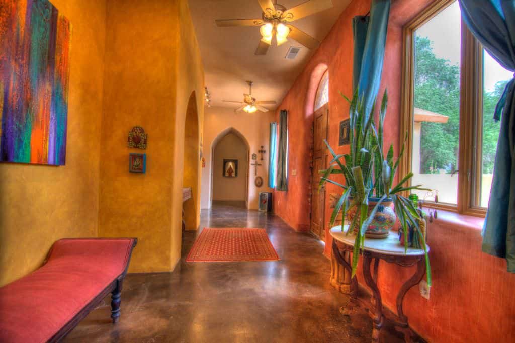 这个色彩丰富的门厅以光滑的墙壁和地板为特色。墙壁装饰和窗帘为家庭增添了风格。侧面的红色座椅看起来也很完美。